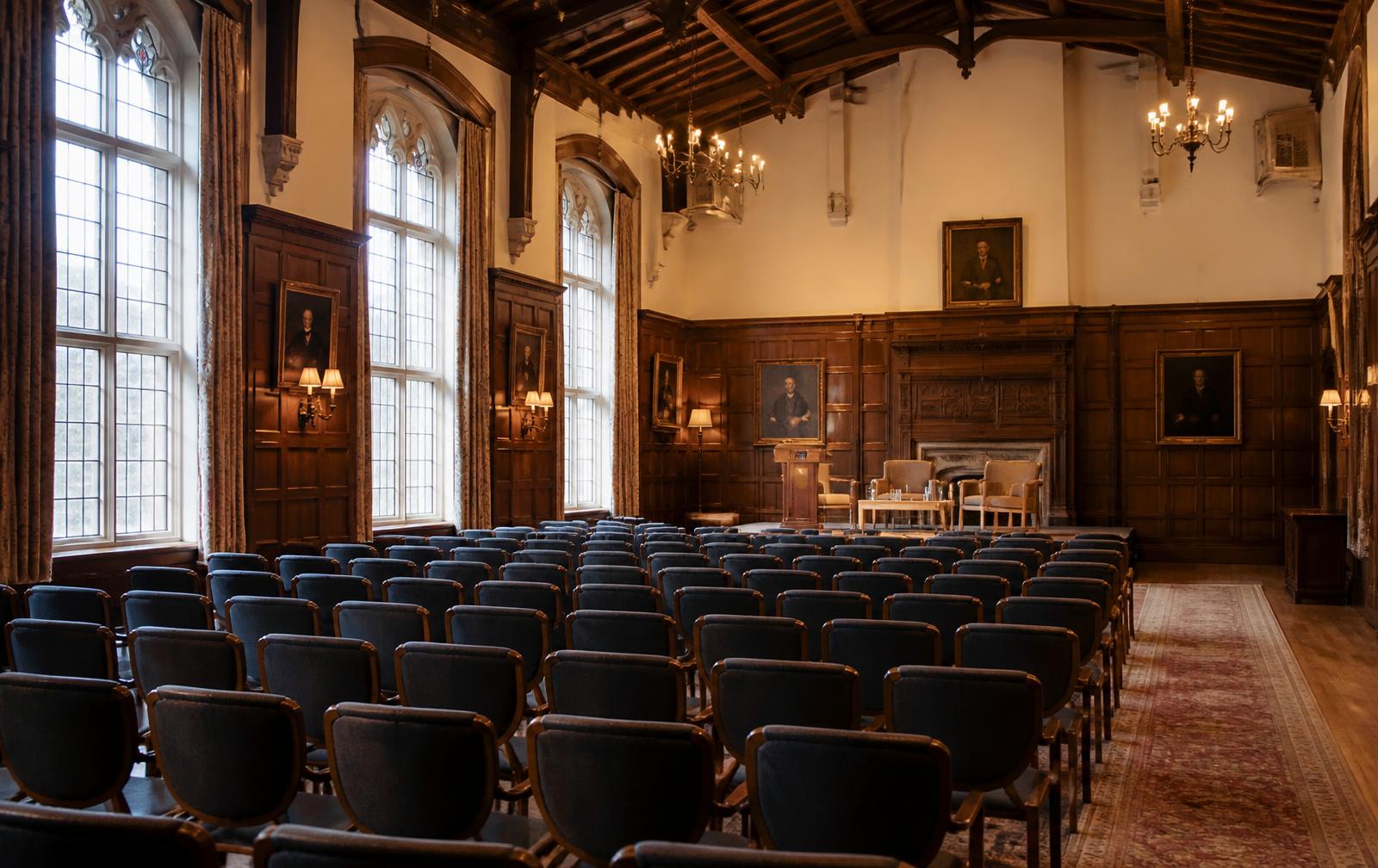 Wood-panelled hall inside the Stanford Faculty Club, set with chairs facing a small stage